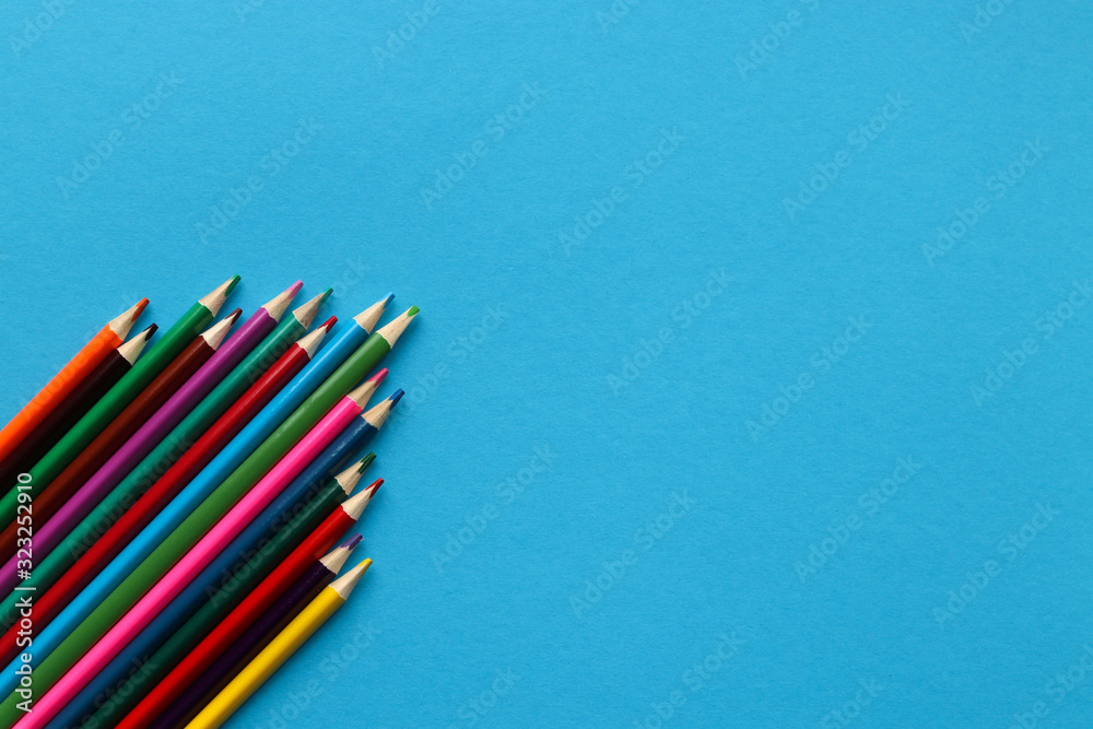 Fototapeta premium Group of multi-colored wooden sharpened pencils on a blue paper background with place for text.