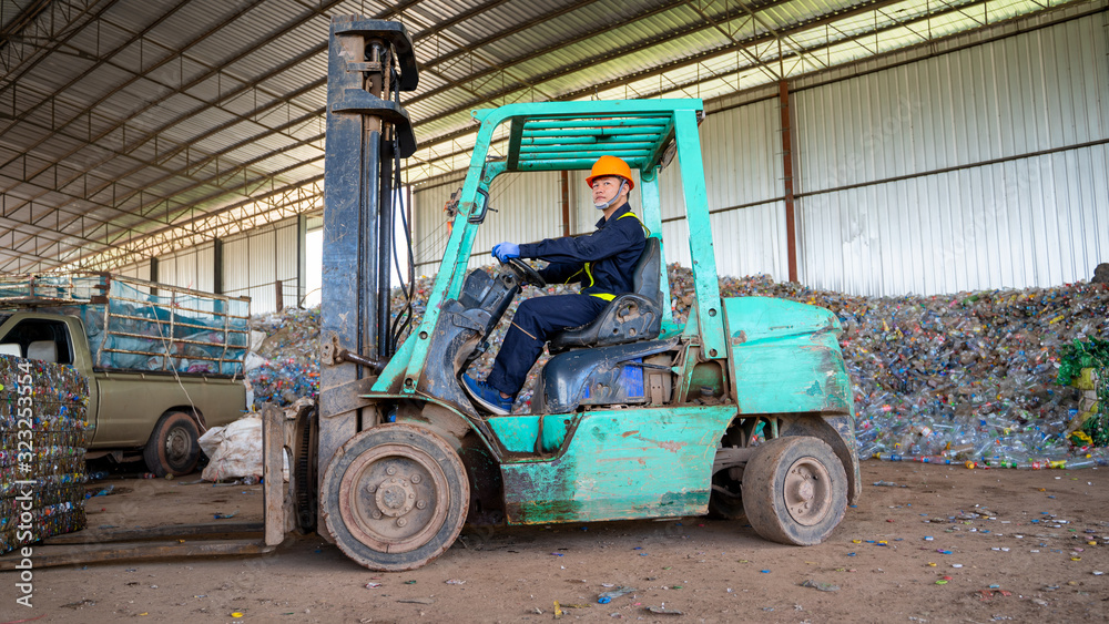 Worker use forklift moving recycling bales in a waste recycling plant.
