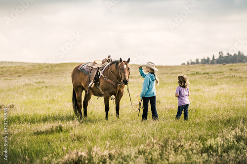 Two young girls with a horse in the prairie. Cody, Wyoming, USA
