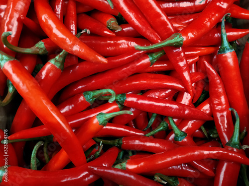 Red hot chilli peppers background. A cluster of red hot chili peppers in a heap at the bottom of the box. Street vegetable market. Packaging, menu, spices, spicy food, food advertisement.