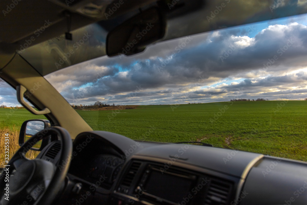 view from the car through the windshield on a green field in the sun