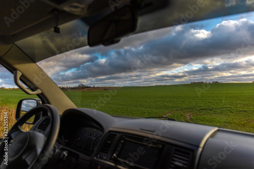 view from the car through the windshield on a green field in the sun © Sergey