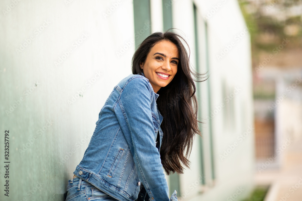 smiling young brunette woman leaning against wall smiling young brunette woman leaning against wall