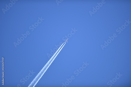 A commercial airplane in the sky and its contrail.