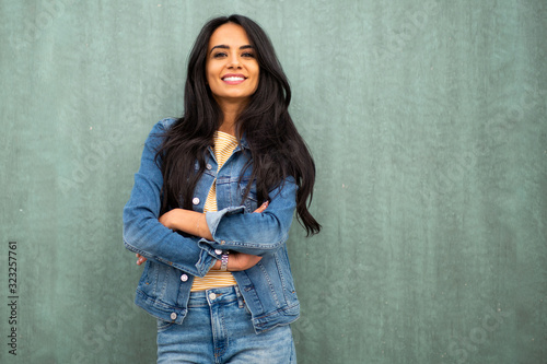 Картината върху платно portrait smiling young latin woman leaning against green wall