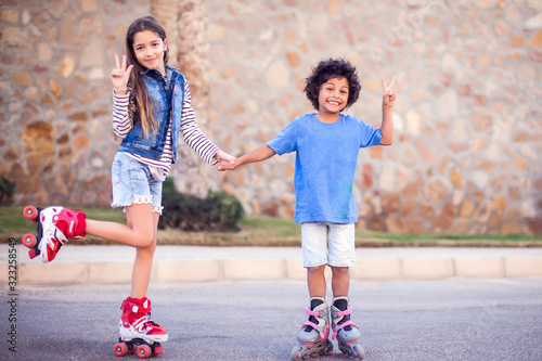 Foto Two happy kids boy and girl roller skate in the park