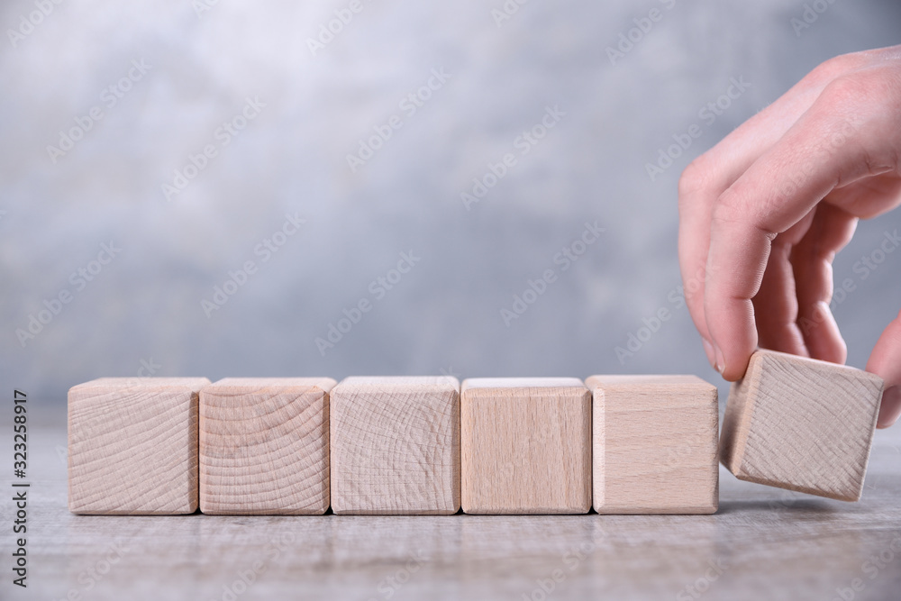 Hand puts blank wooden cube with space for your word, letter, symbol on the table. Place for text, free copy space Hand puts blank wooden cube with space for your word, letter, symbol on the table. Place for text, free copy space