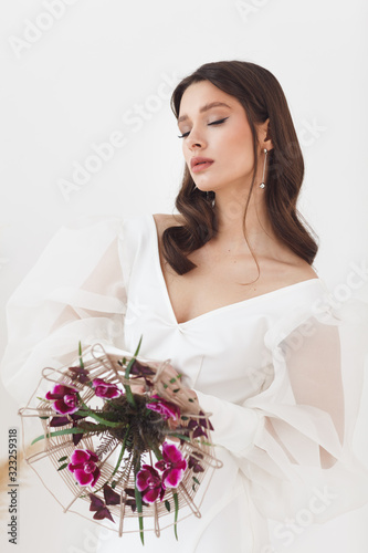 Portrait of elegant beautiful bride with unusual bouquet of flowers. Perfect makeup and hairstyle