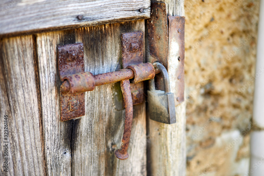 Image of a rusty sliding boor bolt with padlock on old wodden door. Image of a rusty sliding boor bolt with padlock on old wodden door.