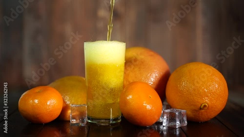 Cold orange drink with ice, oranges and tangerines in a glass glass on a dark background
