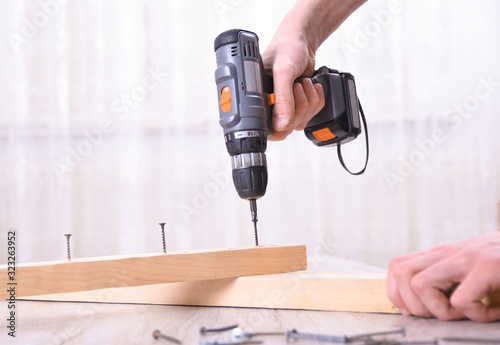 Wallpaper Mural Man is working with furniture assembly using electric screwdriver in new house installation - technician onsite work using hand tools concept Torontodigital.ca