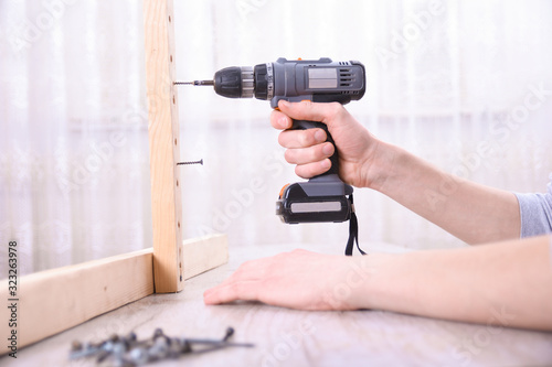 Man is working with furniture assembly using electric screwdriver in new house installation - technician onsite work using hand tools concept