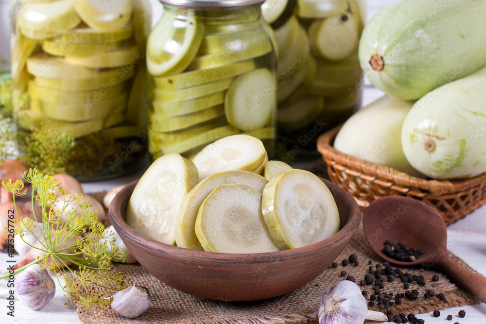 Pickled zucchini in glass jar on a wooden table Pickled zucchini in glass jar on a wooden table