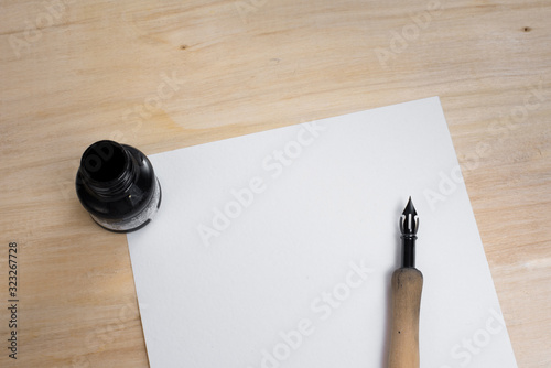 Pen, paper, ink and green flower on a wooden table. Letter in retro style. Calligraphy.