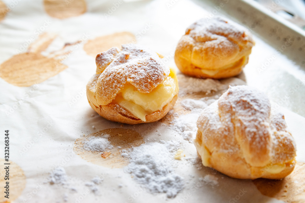 Homemade baking. Freshly baked hot sweet buns sprinkled with powdered sugar and stacked on baking paper on a baking sheet. Homemade baking. Freshly baked hot sweet buns sprinkled with powdered sugar and stacked on baking paper on a baking sheet.