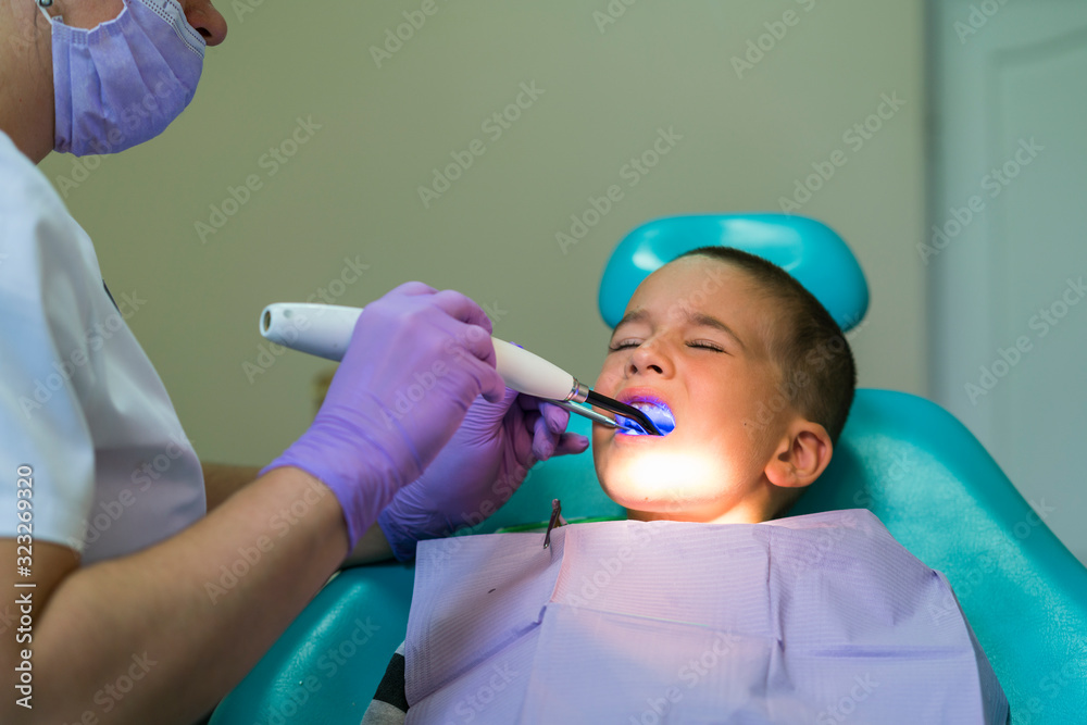 Dentists with a patient during a dental intervention to boy. Dentist Concept. At dentist's office Dentists with a patient during a dental intervention to boy. Dentist Concept. At dentist's office