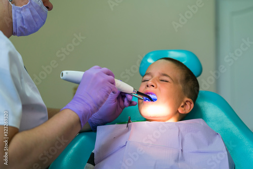 Dentists with a patient during a dental intervention to boy. Dentist Concept. At dentist s office