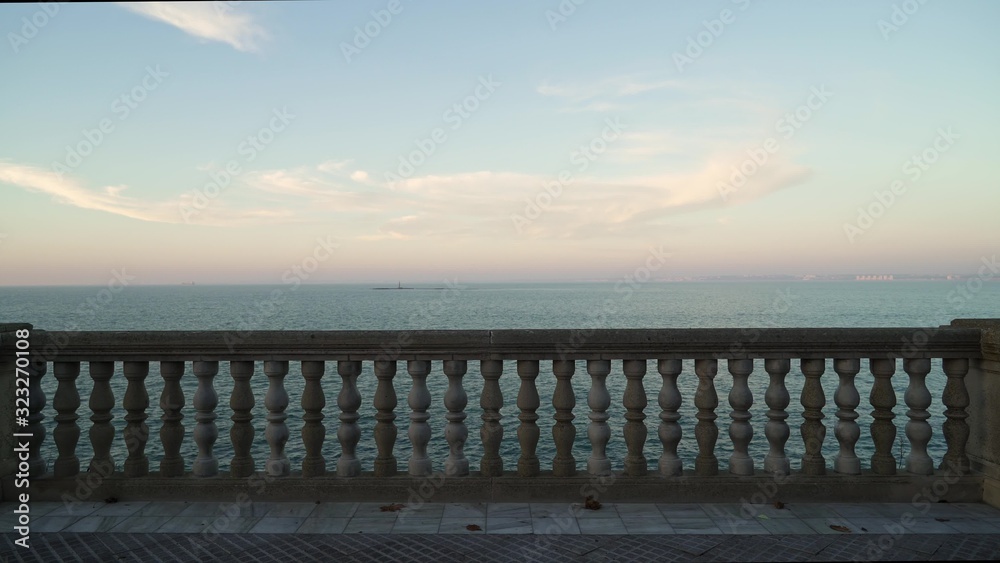 Gimbal shot of marble parapet on quay in Cadiz with a seaview and a tiny island in distance, no people. Cadiz seaview horizon shot from quay