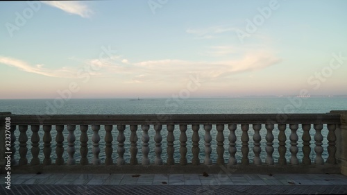 Gimbal shot of marble parapet on quay in Cadiz with a seaview and a tiny island in distance, no people. Cadiz seaview horizon shot from quay