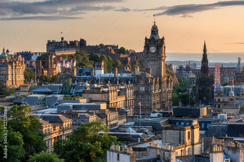 Naklejka premium Wieża zegarowa Balmoral z panoramą miasta Edynburg i tłem zamku w Edynburgu podczas zachodu słońca