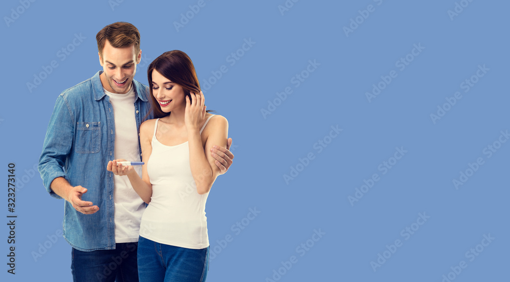 Love, new parents and happy family concept - young happy couple, finding out results of a pregnancy test. Blue color background. Copy space for some text. Love, new parents and happy family concept - young happy couple, finding out results of a pregnancy test. Blue color background. Copy space for some text.