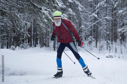 An elderly man skiing in winter.Cross country in the winter in the woods.
