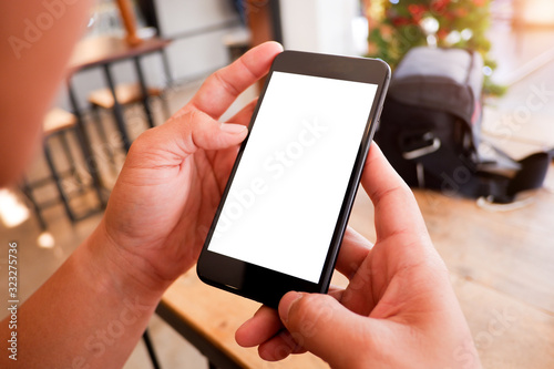 Mockup picture of business man’s hands holding smart phone with white blank screen in modern place.