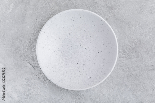 Empty white plate on gray concrete stone background.