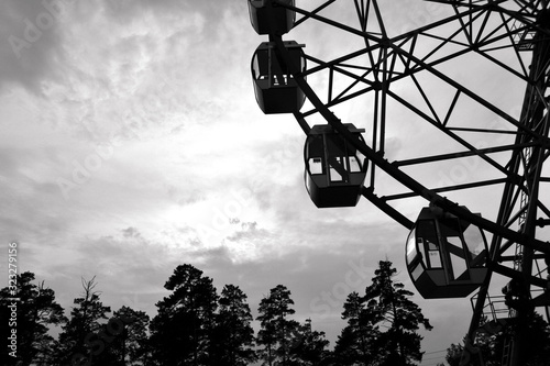Monochrome photo. Big wheel in the city park at sunset. Rest in the amusement park