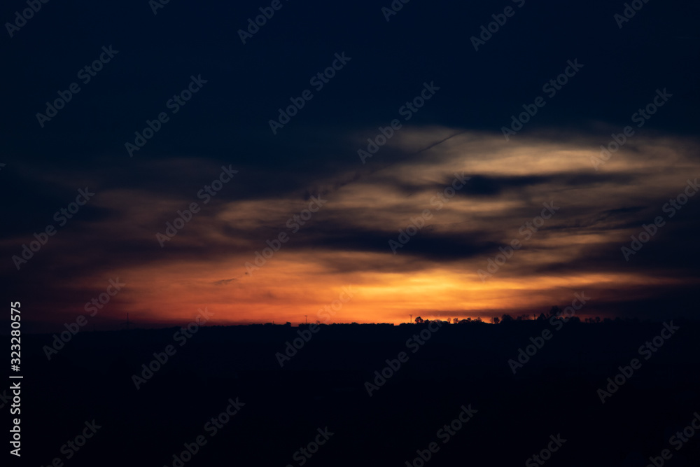 A distant silhouette of a tree line in front of a dramatic sunrise