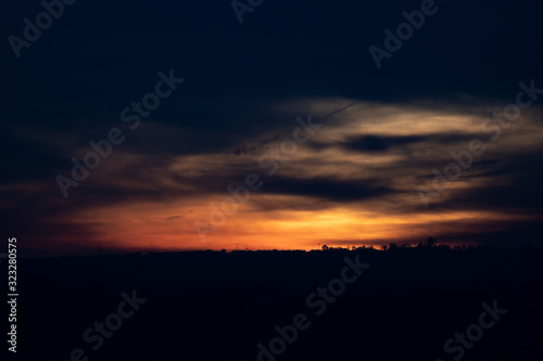 A distant silhouette of a tree line in front of a dramatic sunrise