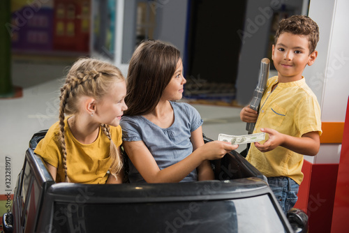 Kids paying money at toy petrol station. Child boy taking money and looking at camera. City of profession for children. photo