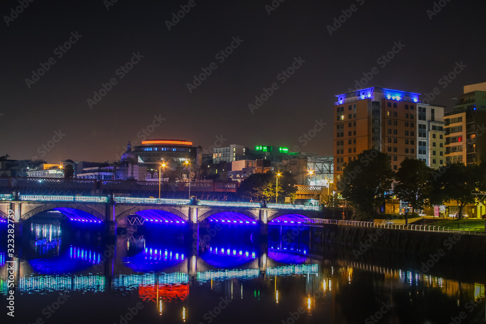 Glasgow cityscape at night, view of the bridges over a river illuminated by neon and LED lights.