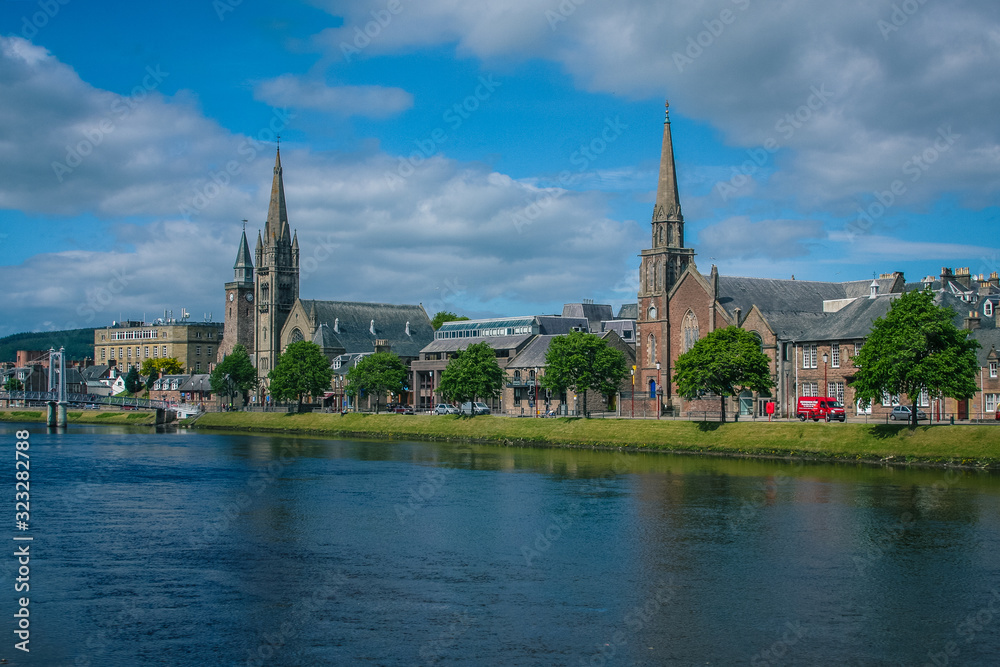 Cityscape of Inverness over river Ness, Old High Church and Free Church are visible on a sunny day.