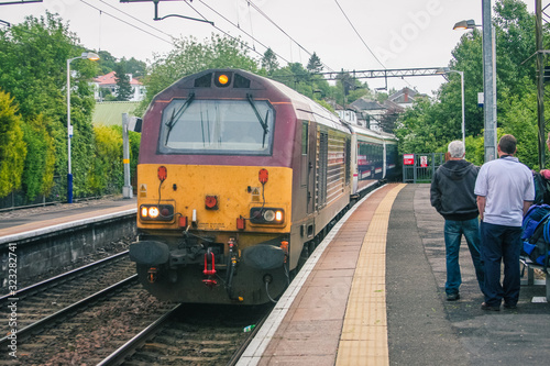 Famous scottish caledonian sleeper train is arriving to a platform on a train station on its way to Fort William on a cloudy day.