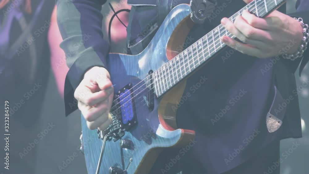 A virtuoso guitarist playing an electric guitar on stage with flashing LED lights.