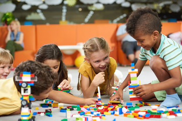 31.07.2017 - Kyiv, Ukraine. Group of funny kids playing with block toys indoor. Cute kids playing together indoor. Preschool early education.