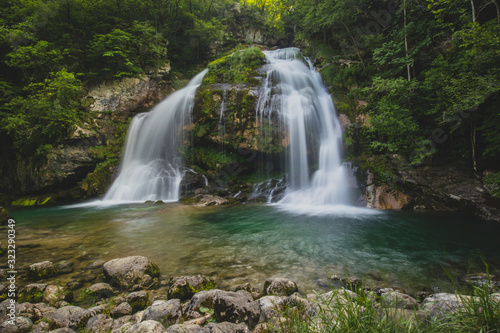 Fototapeta Naklejka Na Ścianę i Meble -  Long exposure of magical looking Virje waterfall in Slovenia, close to bovec. Dreamy and enchanting water falling down the cliff above the small alpine lake.