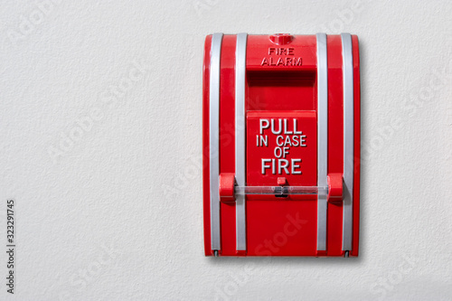 Wall-mounted fire alarm pull station. Connected to fire panel in building. Activates alarm to fire hall and sound for building evacuation. Copy space.