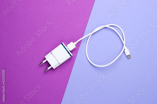Charger with cable on colored background. Top view