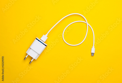 Charger with cable on a yellow background. Top view