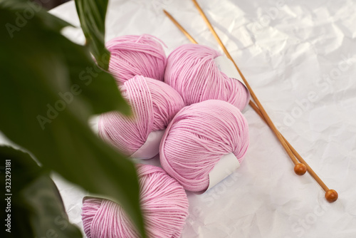 balls of pink yarn and wooden knitting needles on a white background