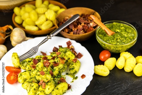 Homemade gnocchi with spinach and Prosciutto on black slate board. Traditional italian food. Potato gnocchi. Gnocchi with spinach and garlic.