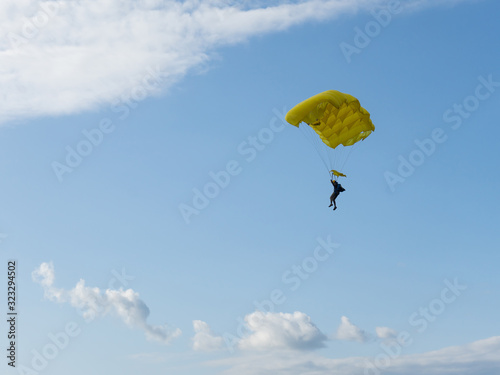 Parachuter descending with parachute against blue sky. Skydiver in the sky. People under parachute in the sky. © Dmitrii