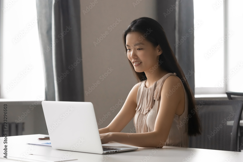 Millennial Asian woman busy working on laptop in office Millennial Asian woman busy working on laptop in office