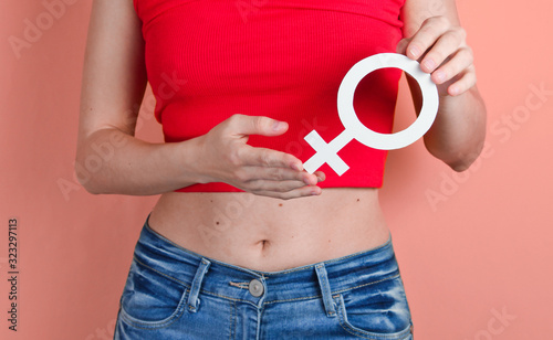 Femen concept. Woman holds in her hand gender feminism symbol on pink background. Crop photo, studio shot photo