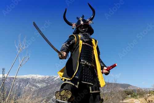 Samurai warrior dressed in armor, posing in the mountain