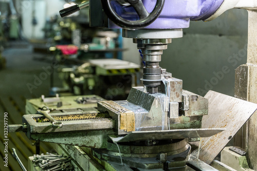 A process of old-style manual milling in weathered vise with liquid coolant., Close-up with selective focus and background bliur, photo