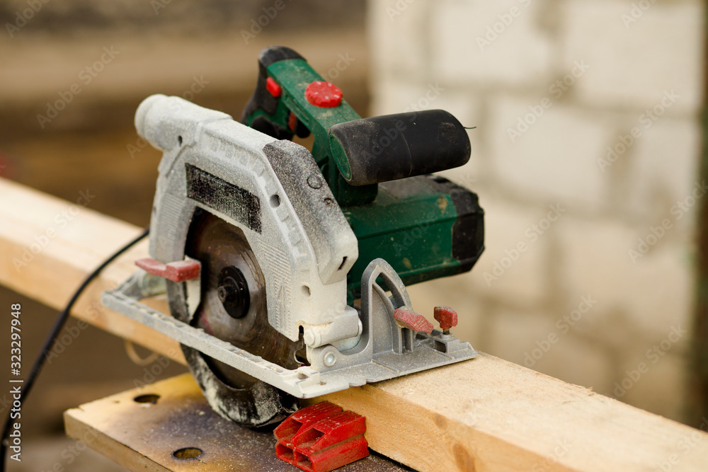 A modern green circular saw lies on a wooden table in the workshop. Closeup of a circular saw