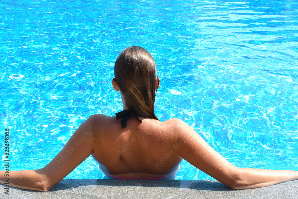 Portrait of a girl in the pool. A woman swims in the pool. Summer vacation in the summer on the water. Spa vacation.